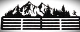 Metal art design of a mountain landscape with trees and a fence.